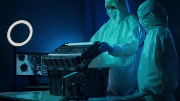 Wissenschaftler in Schutzanzügen und Masken arbeiten im Forschungslabor mit Laborausrüstung: Mikroskope, Reagenzgläser. Coronavirus covid-19 Hazard, pharmazeutische Entdeckung, Bakteriologie und Virologie - Filmmaterial, Video