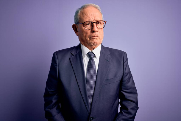 Grey haired senior business man wearing glasses and elegant suit and tie over purple background depressed and worry for distress, crying angry and afraid. Sad expression. - Fotoğraf, Görsel