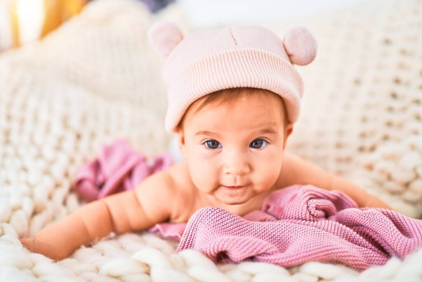 Evdeki kanepede battaniyenin üzerine uzanmış sevimli bir bebek. Yenidoğan bel şapkası takıyor. Rahatlıyor ve dinleniyor. - Fotoğraf, Görsel