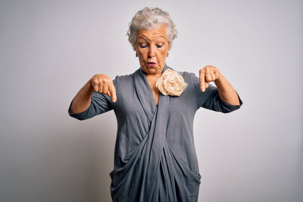 Senior beautiful grey-haired woman wearing casual dress standing over white background Pointing down with fingers showing advertisement, surprised face and open mouth - Photo, Image