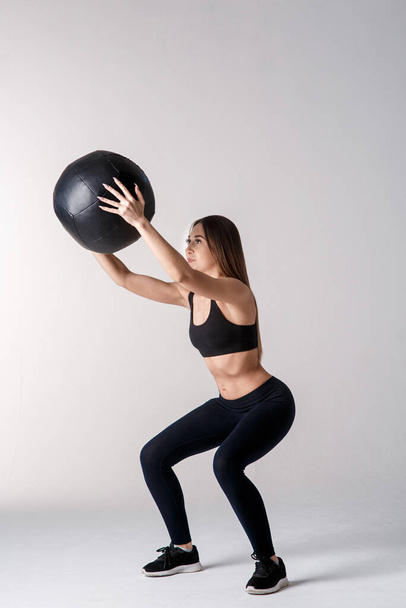 Athletic woman doing exercise with med ball. Photo of sporty latin woman in fashionable sportswear on white background. Strength and motivation. - Zdjęcie, obraz