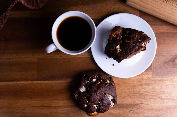 Delicious cookie cakes with chocolate with a cup of coffee on a wooden board with copy space - Zdjęcie, obraz
