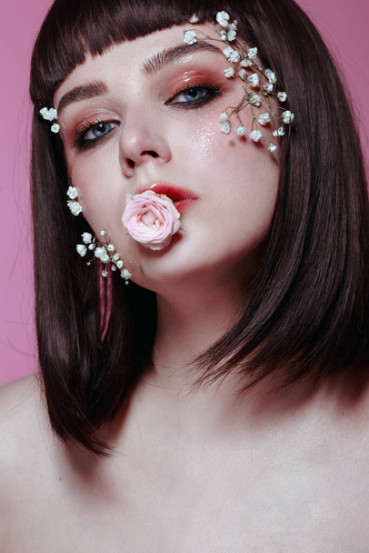 Close up studio beauty portrait of young beautiful woman with fresh, smooth, flawless skin, nude makeup with flower on pink background. Fashion photo - Foto, imagen