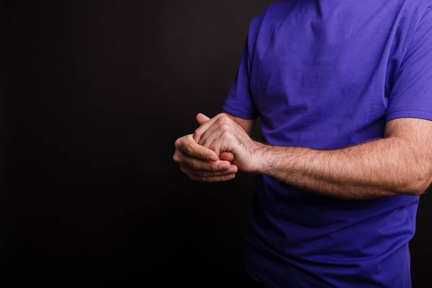 A closeup of a man using a hand sanitiser against a black background - COVID-19 - Φωτογραφία, εικόνα