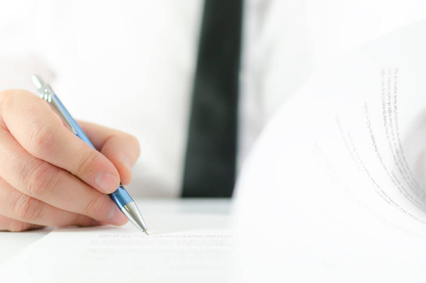 Close-up van de zakenman die een pagina van het contract omdraait en ondertekent met een pen - Foto, afbeelding