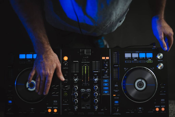 A closeup of a DJ working under the colourful lights in a studio - Photo, Image