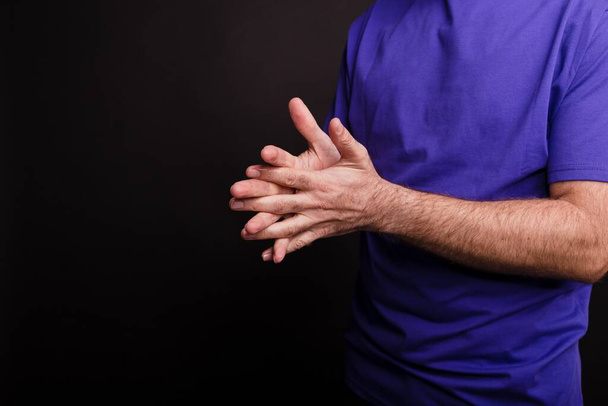 A closeup of a man using a hand sanitiser against a black background - COVID-19 - Foto, imagen
