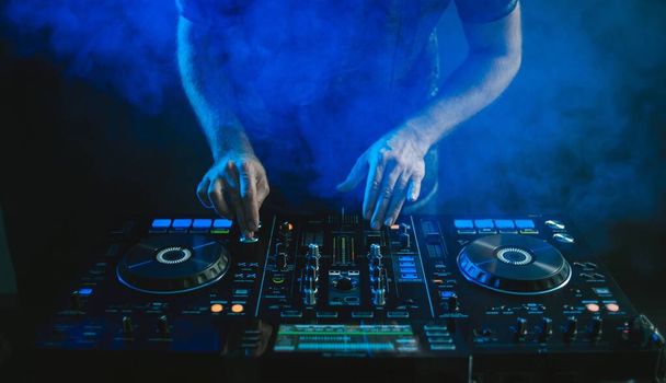 Gros plan d'un DJ travaillant sous les lumières bleues sur un fond sombre dans un studio
 - Photo, image