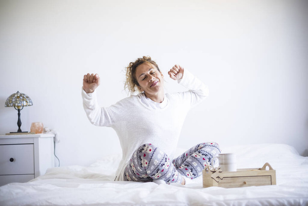 Early morning wake up concept with happy cheerful caucasian beautiful adult woman stretching and smiling  - Photo, Image