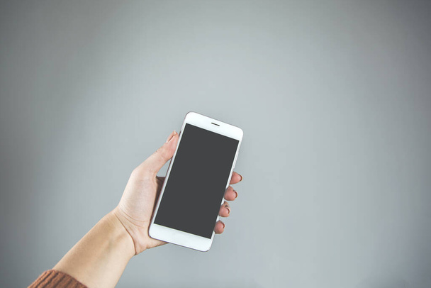 woman hand holding smart phone on gray background - Foto, afbeelding