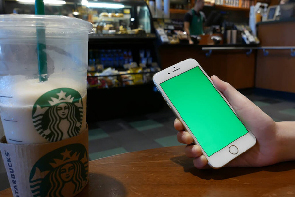 Port Coquitlam, BC, Canadá - 28 de julio de 2016: Mano sosteniendo iphone pantalla verde dentro de la tienda Starbucks
 - Foto, imagen