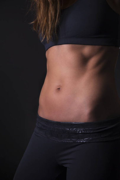 Female abdominal muscles on black background  - Фото, изображение