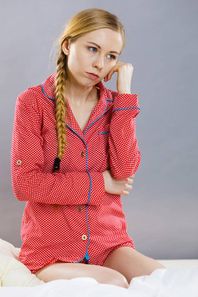 Adolescence problems concept. Sad young teenager woman sitting on bed feeling depressed. - Foto, afbeelding