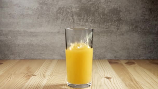Glass with orange juice. Ice cube fall, creating a lot of splashing. Slow motion - Video