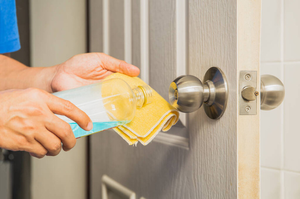 Pomo de puerta de limpieza manual con alcohol y paño de microfibra amarilla. Protección infectada por el virus Corona
 - Foto, Imagen