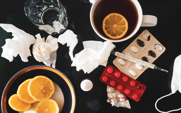 Лечение простуды и гриппа. Различные лекарства, термометр, спреи для душного носа и боли в горле, чай с ломтиком лимона
 - Фото, изображение