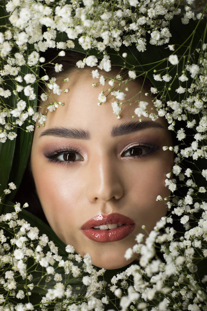 Portrait of beautiful girl with small white flowers around her face. Woman and flowers. Spring. - Foto, imagen