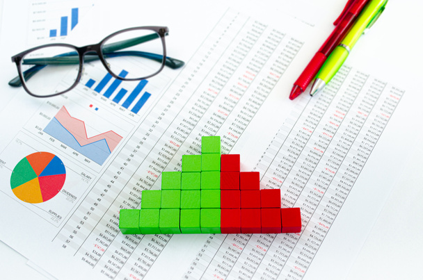 Financiële documenten, met groene en rode blokjes in een kolom grafiek als concept voor inkomsten, uitgaven of ontvangsten - Foto, afbeelding
