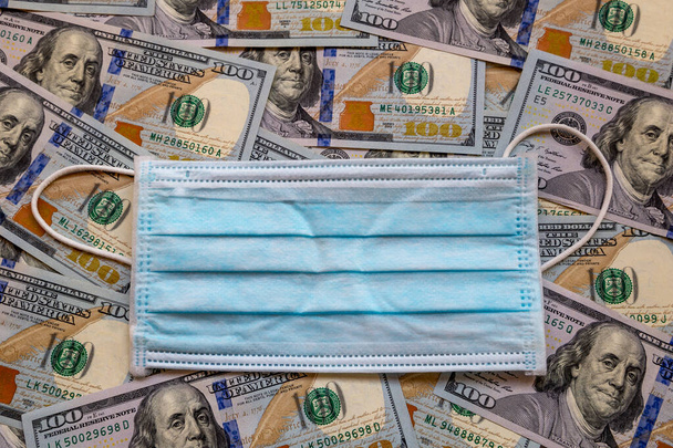 Amerika Birleşik Devletleri banknotları ve virüse karşı koruyucu bir maske. Coronovirüs ile ilişkili dünya ekonomik krizi. - Fotoğraf, Görsel
