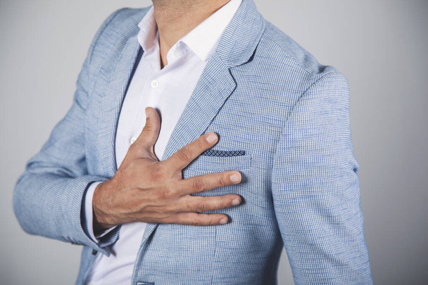 man hand on ache heart on gray background - Photo, Image