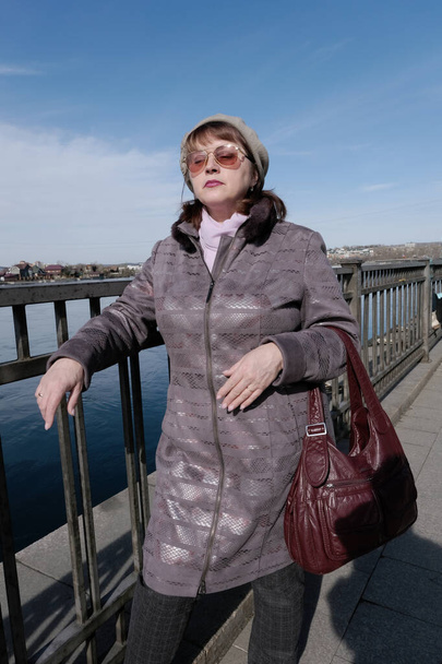 Μια ηλικιωμένη γυναίκα στέκεται στο φράχτη στο ανάχωμα Angara στο Ιρκούτσκ - Φωτογραφία, εικόνα
