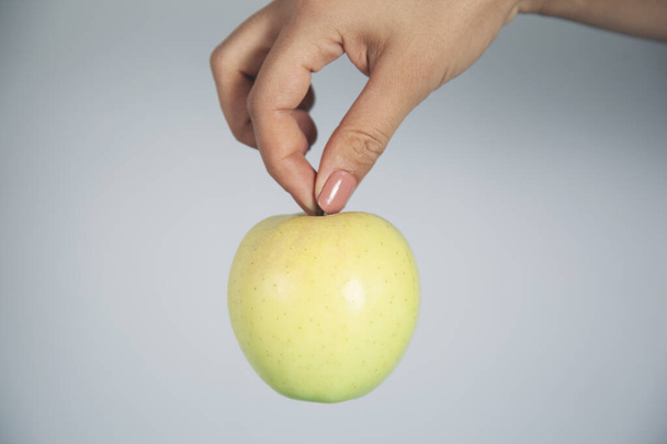 woman hand green apple on gray background - Photo, Image