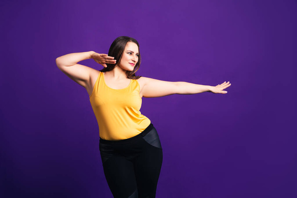Happy plus size fashion model in casual clothes, cheerful fat woman on purple background, body positive concept - Foto, afbeelding