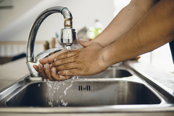 Zawsze należy zacząć od czystych rąk, aby zapobiec rozprzestrzenianiu się koronawirusu (Covid-19). Ujęcie azjaty myjącego ręce w domu. - Zdjęcie, obraz
