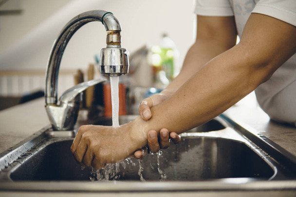 Iniziare sempre con le mani pulite per evitare la diffusione del coronavirus (Covid-19). Ritagliato colpo di un asiatico uomo lavaggio le mani a casa
 - Foto, immagini