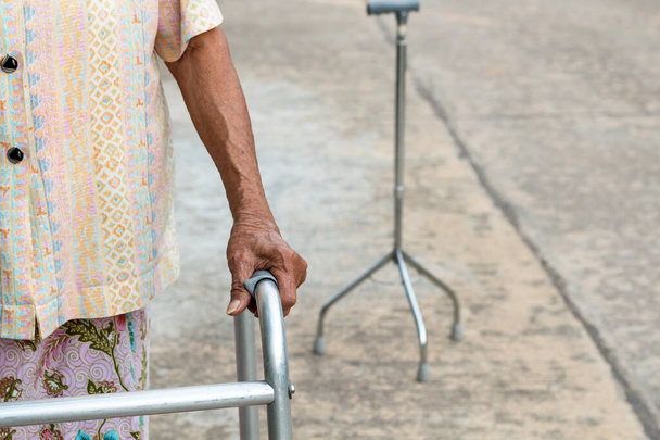 Asyalı yaşlı bir kadın elleri baston üzerinde, elinde değnek tutan yaşlı bir kadın. - Fotoğraf, Görsel