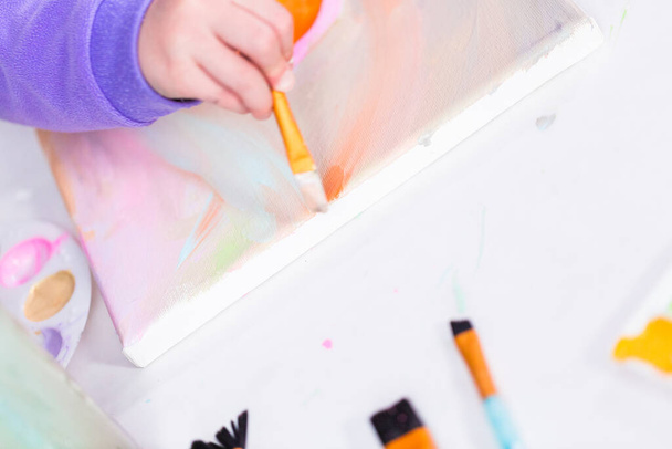 Маленька дівчинка малює на полотні з арктичною фарбою
. - Фото, зображення