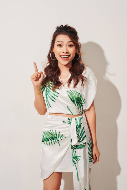 Cute asian woman in tropical print green dress thinking and imagination on white background - 写真・画像