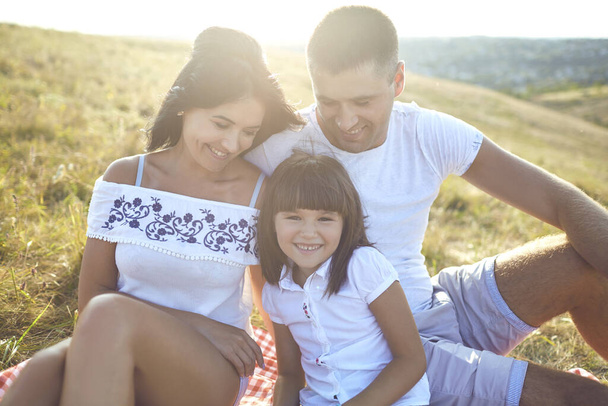 Happy family on a picnic outdoors at sunset. - 写真・画像