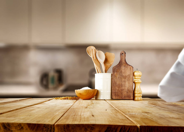 Kitchen tools and utensils on wooden table. Blurred kitchen interior. Space for your decoration.  - Foto, imagen