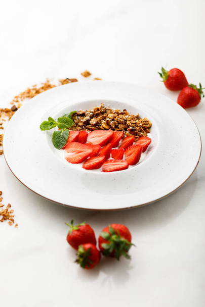 granola con fresa y menta en plato blanco
 - Foto, Imagen