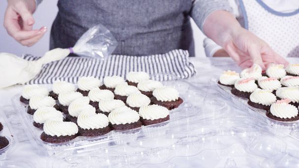 Askel kerrallaan. Pieni tyttö auttaa koristella mini suklaa cupcakes suklaa lumihiutaleet. - Valokuva, kuva