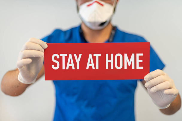 Врач с красной бумагой, который сидит дома, держа под рукой, защищает от коронавируса или эпидемии Ковид-19
 - Фото, изображение