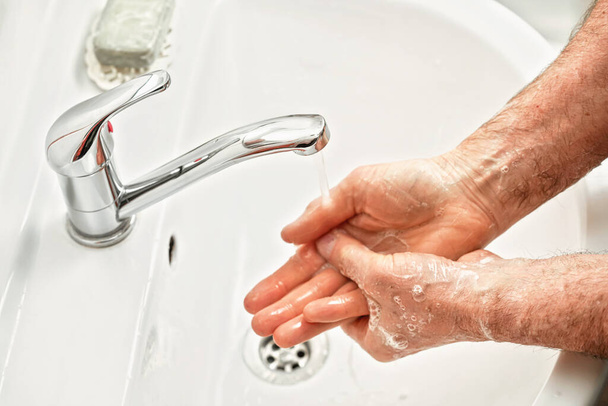 Senior elderly man his hands palms with soap under tap water faucet, detail photo. Can be used as hygiene illustration concept during ncov coronavirus / covid-19 outbreak prevention - Fotó, kép