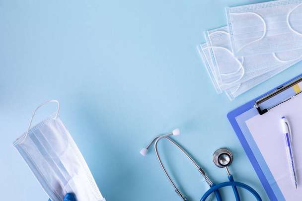 medical concept on a blue background. stethoscope, pills, tablet, notepad, sheet of paper, pen. Medical mask - 写真・画像