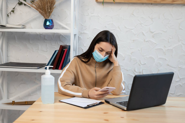 Nainen tyttö yllään suojaava naamio korkea kuume ja päänsärky, toimii kannettavan tietokoneen aikana karanteeni koronavirus
, - Valokuva, kuva
