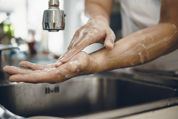 Always start with clean hands to prevent spreading of the coronavirus (Covid-19). Cropped shot of an asian man washing his hands at home - Foto, Bild