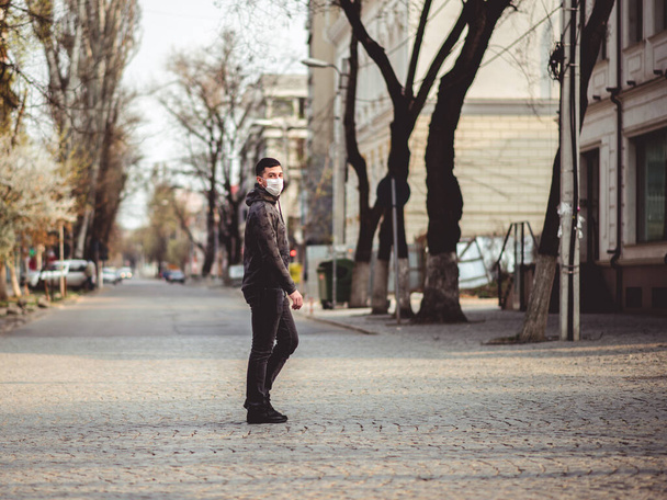 Cowid-19 virus. A man in a medical mask is walking on an empty street in the city. Pandemic mask virus protection. - Фото, зображення