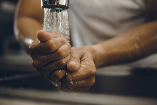 Always start with clean hands to prevent spreading of the coronavirus (Covid-19). Cropped shot of an asian man washing his hands at home - Foto, imagen