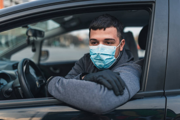 Mann mit medizinischer Maske und Gummihandschuhen zum Schutz vor Bakterien und Viren während der Autofahrt. Maskierter Mann in einem Auto. Coronavirus, Krankheit, Infektion, Quarantäne, Covid-19 - Foto, Bild