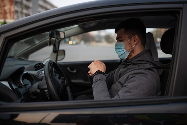 A man sits car and washes his hands with antiseptic gel. healthcare concept in car. The mask is white on the face. coronavirus, disease, infection, quarantine, covid-19 - Photo, Image