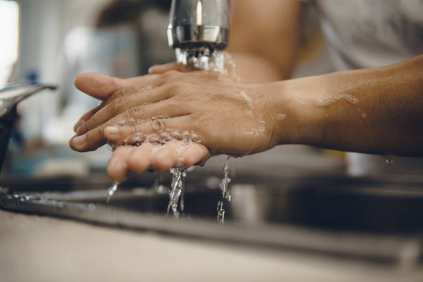 Always start with clean hands to prevent spreading of the coronavirus (Covid-19). Cropped shot of an asian man washing his hands at home - Photo, image