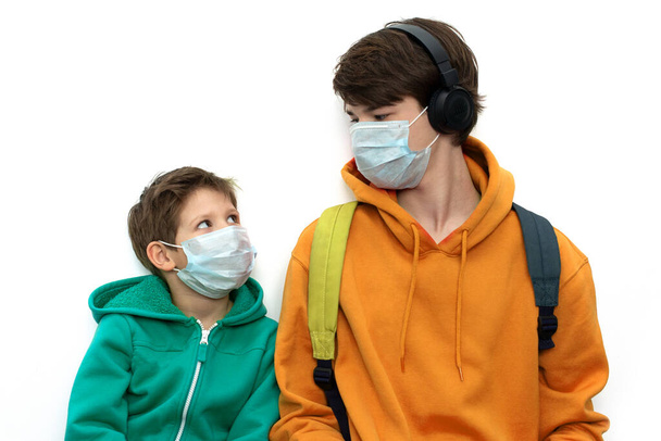 παιδιά με ιατρικές μάσκες με φωτεινά ρούχα, απομονωμένα, αντιγραφή χώρου. Προστασία από τον ιό του κερατοειδούς. - Φωτογραφία, εικόνα
