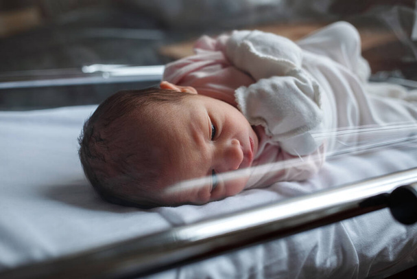 Novorozené dítě v nemocnici. Dítě se právě narodilo. Ospalé dítě leží v postýlce. - Fotografie, Obrázek
