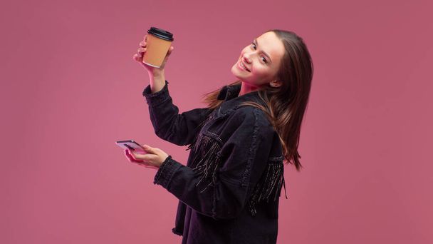 young student with a cardboard coffee Cup and a smartphone in her hands. - Foto, afbeelding