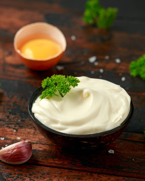 Mayonnaise sauce in a wooden bowl with egg, mustard, garlic and herbs - Photo, Image